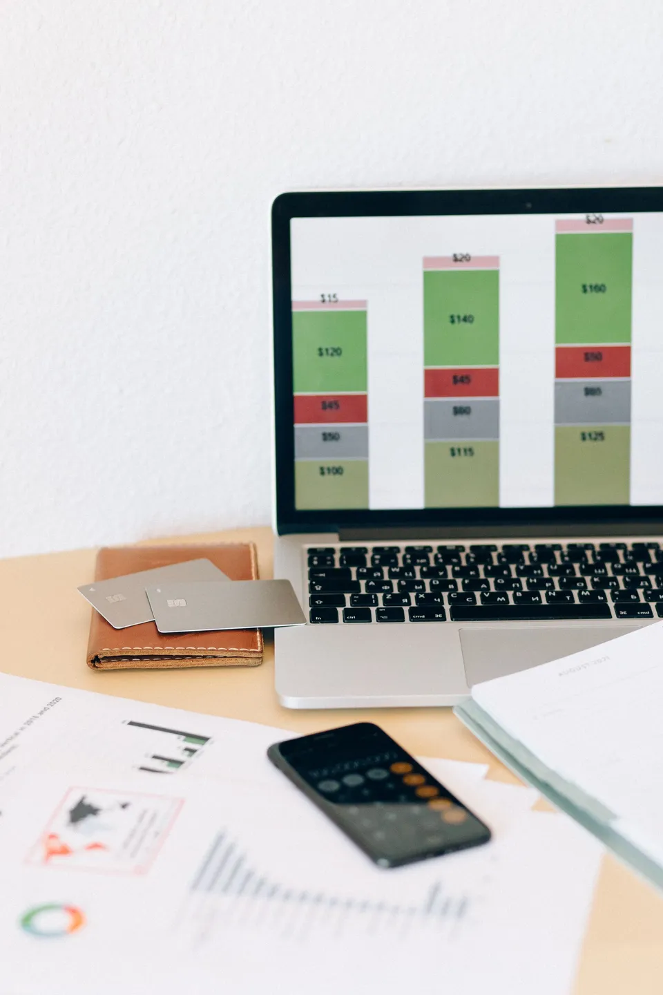 Ordinateur affichant un suivi financier, calculatrice et documents sur un bureau