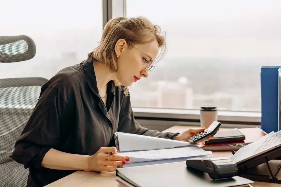 Professionnelle vérifiant des documents avec une calculatrice, illustration
