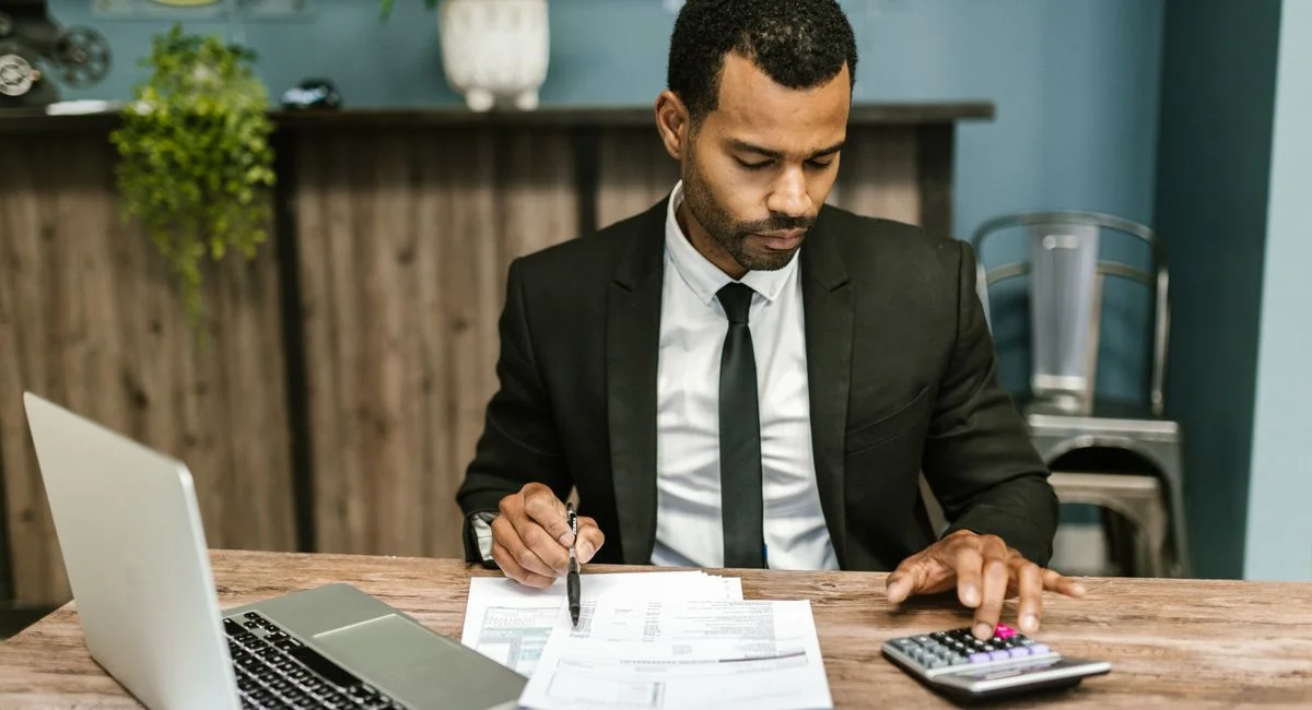 A focused businessman works with a calculator and documents in a modern office.