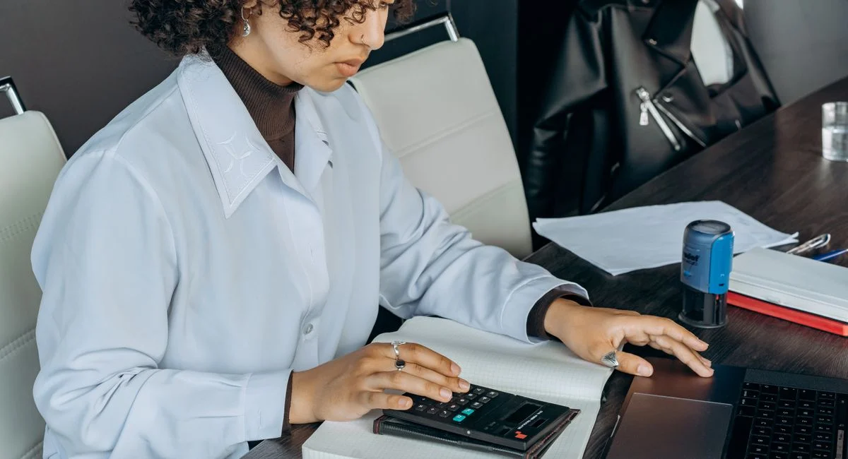 Young woman in office using a calculator for financial calculations.