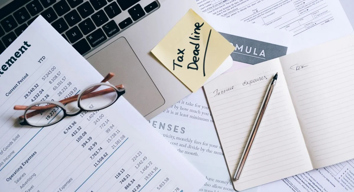 Workspace with laptop, documents, and tax deadline note for financial management.