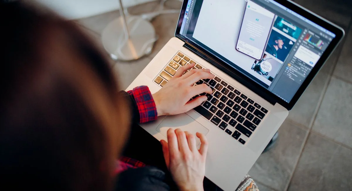 Close-up of a person working on a laptop with graphic design software.