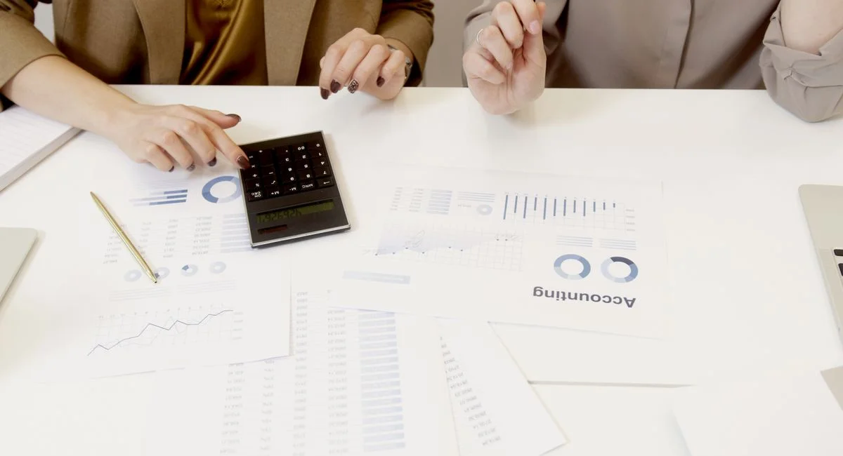 Two professionals analyzing financial documents with a calculator.
