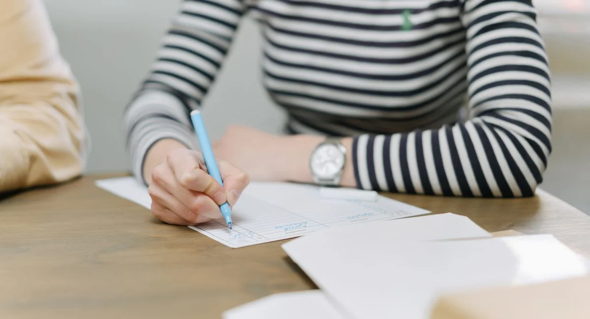Adult writing with colored pen on documents, emphasizing strategic planning.