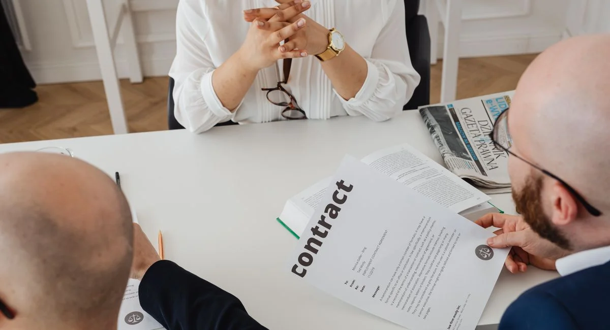 Business professionals discussing a contract in a modern office setting.